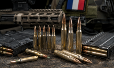 Cartouches de 5,56 et 7,62 mm devant un fusil et un drapeau français