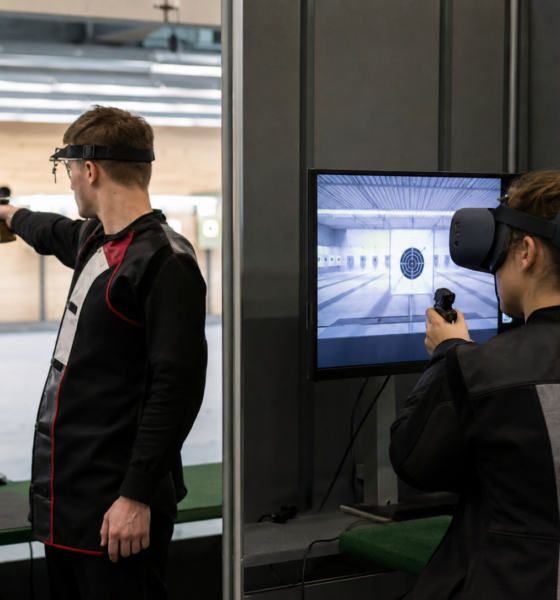 Un tireur au pistolet à côté d'une personne équipée d'un casque de réalité virtuelle sur un pas de tir
