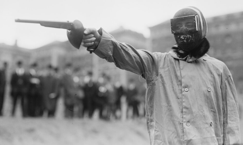 Duelliste masqué en sarrau de protection pointant un pistolet de duel, New York, vers 1909