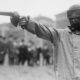Duelliste masqué en sarrau de protection pointant un pistolet de duel, New York, vers 1909