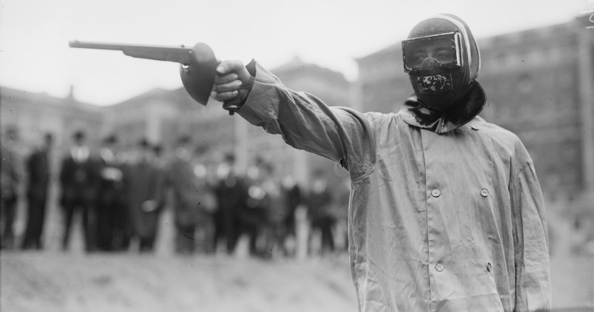 Duelliste masqué en sarrau de protection pointant un pistolet de duel, New York, vers 1909